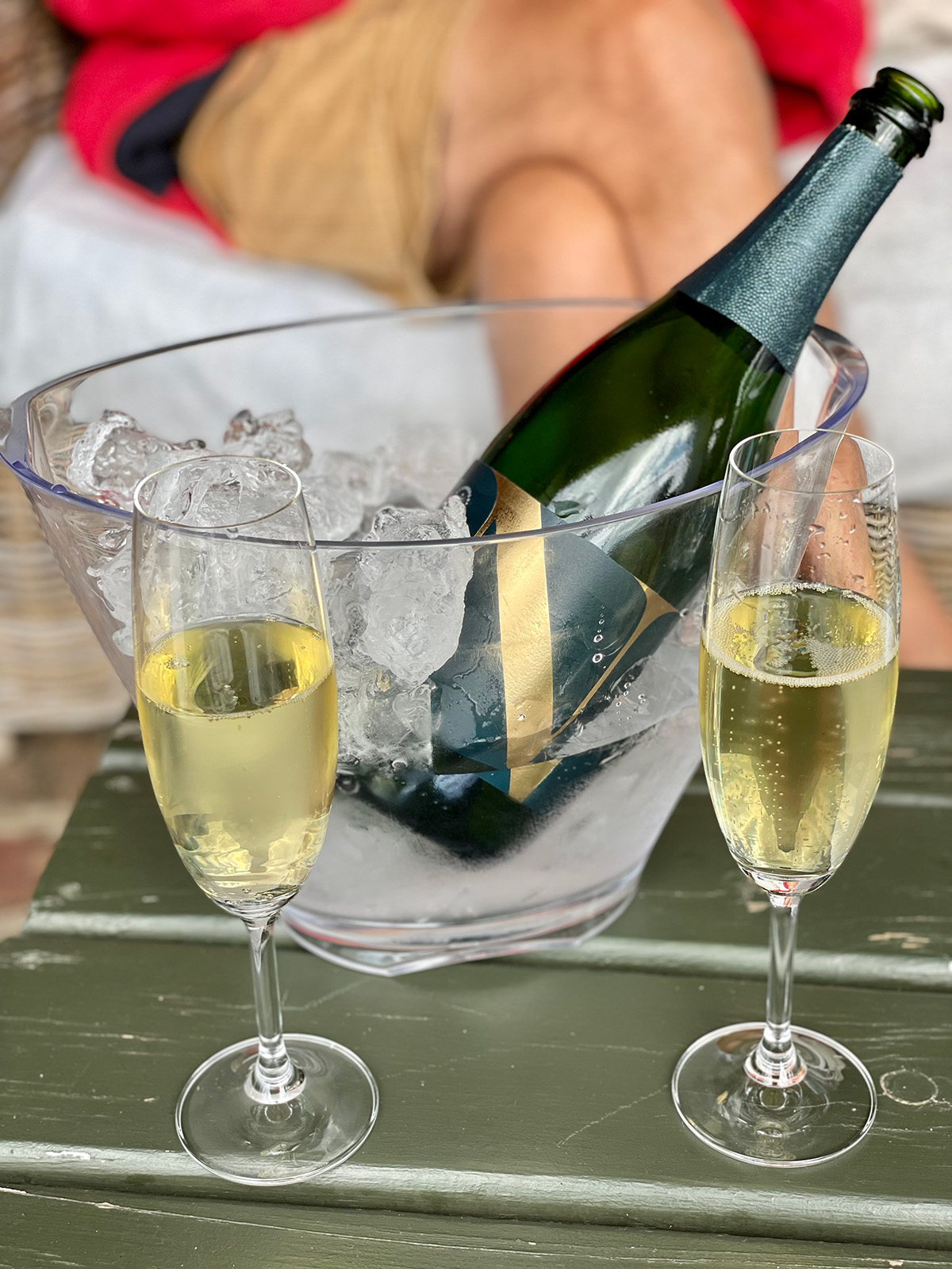 Een fles bubbels van wijnhuis Newstad met twee gevulde champagne glazen erbij